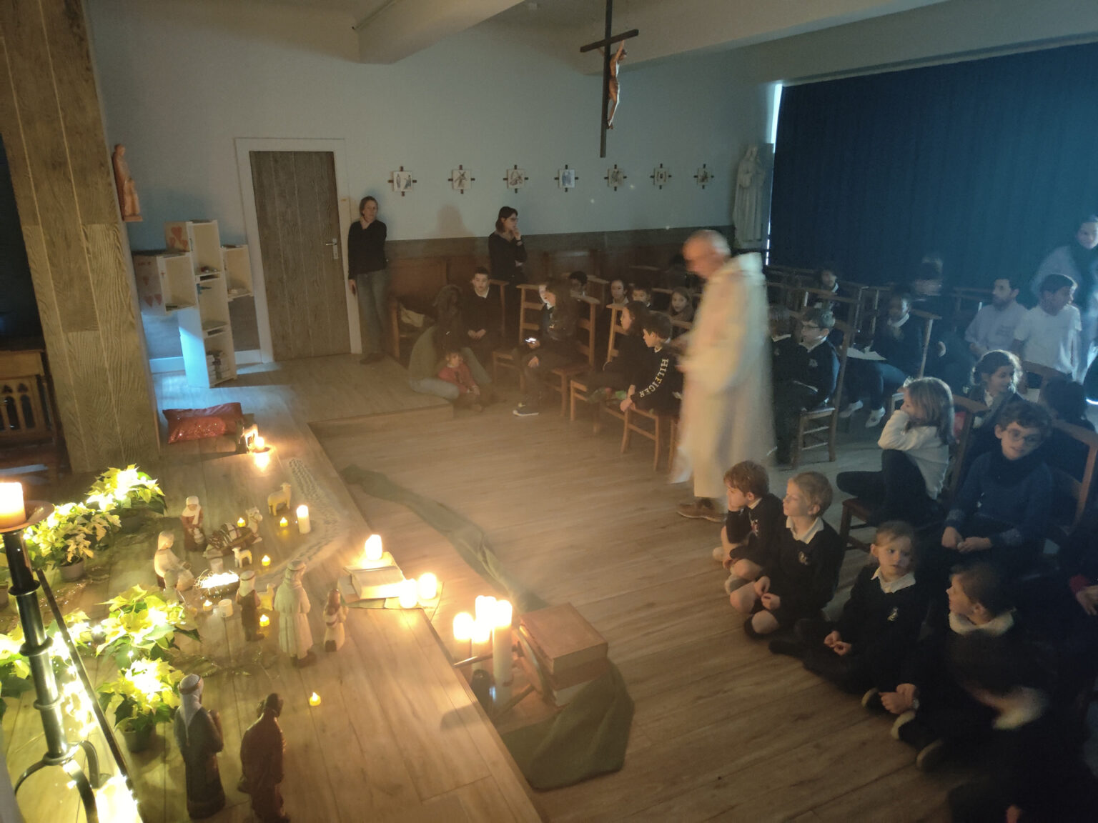 Temps de recueillement dans la chapelle du Collège Saint-Pierre Les Servites de Marie, avec des élèves rassemblés autour d’une crèche et de bougies allumées.